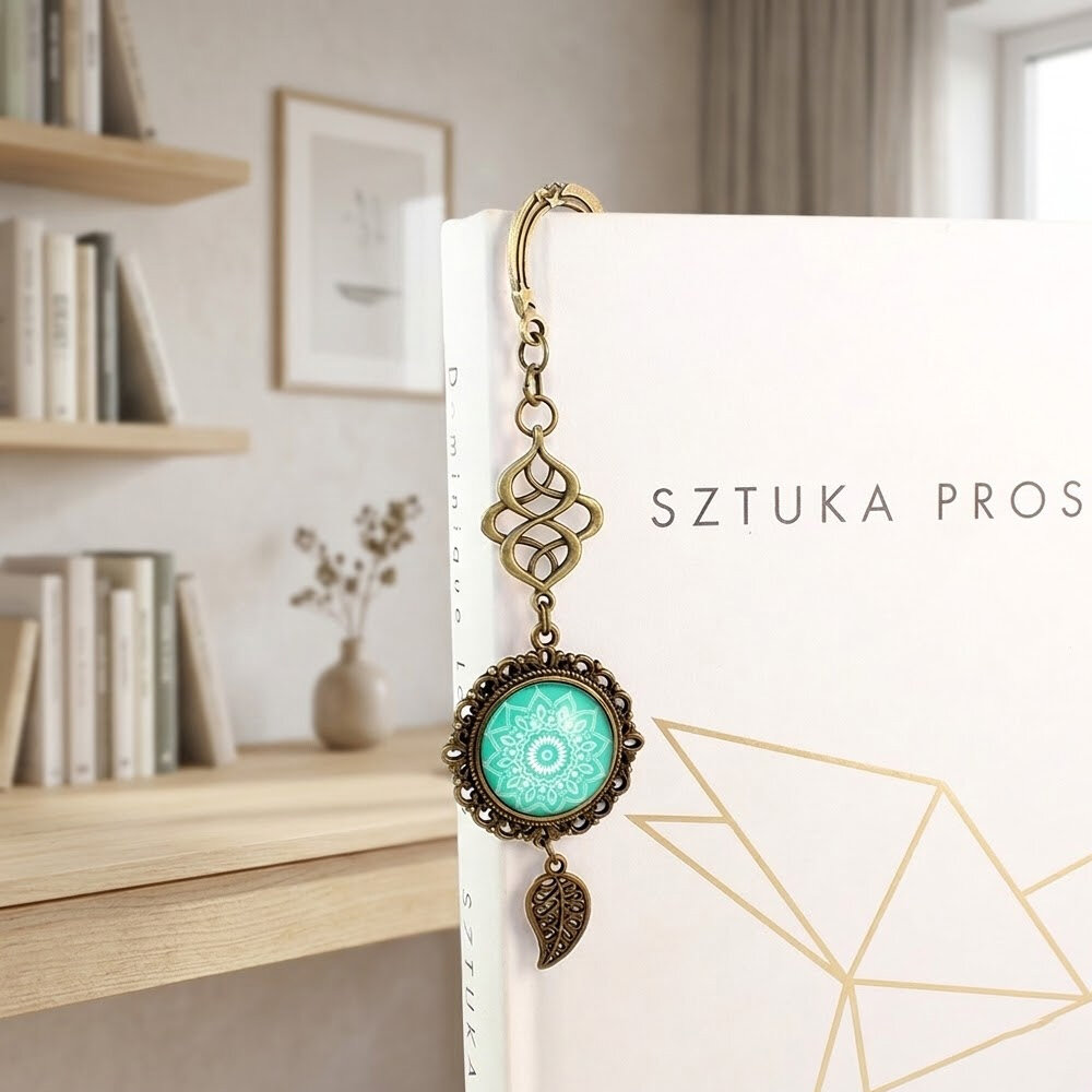 Zakładka do książki z antycznego brązu o falistym trzonie, z ozdobnym koralikiem i uspokajającą, turkusową mandalą pod szklanym kaboszonem.