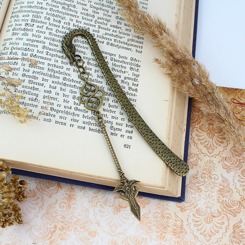 Zakładka do książki z antycznego brązu z motywem łusek smoka i zawieszką w kształcie dużej, zdobionej włóczni w stylu fantasy.