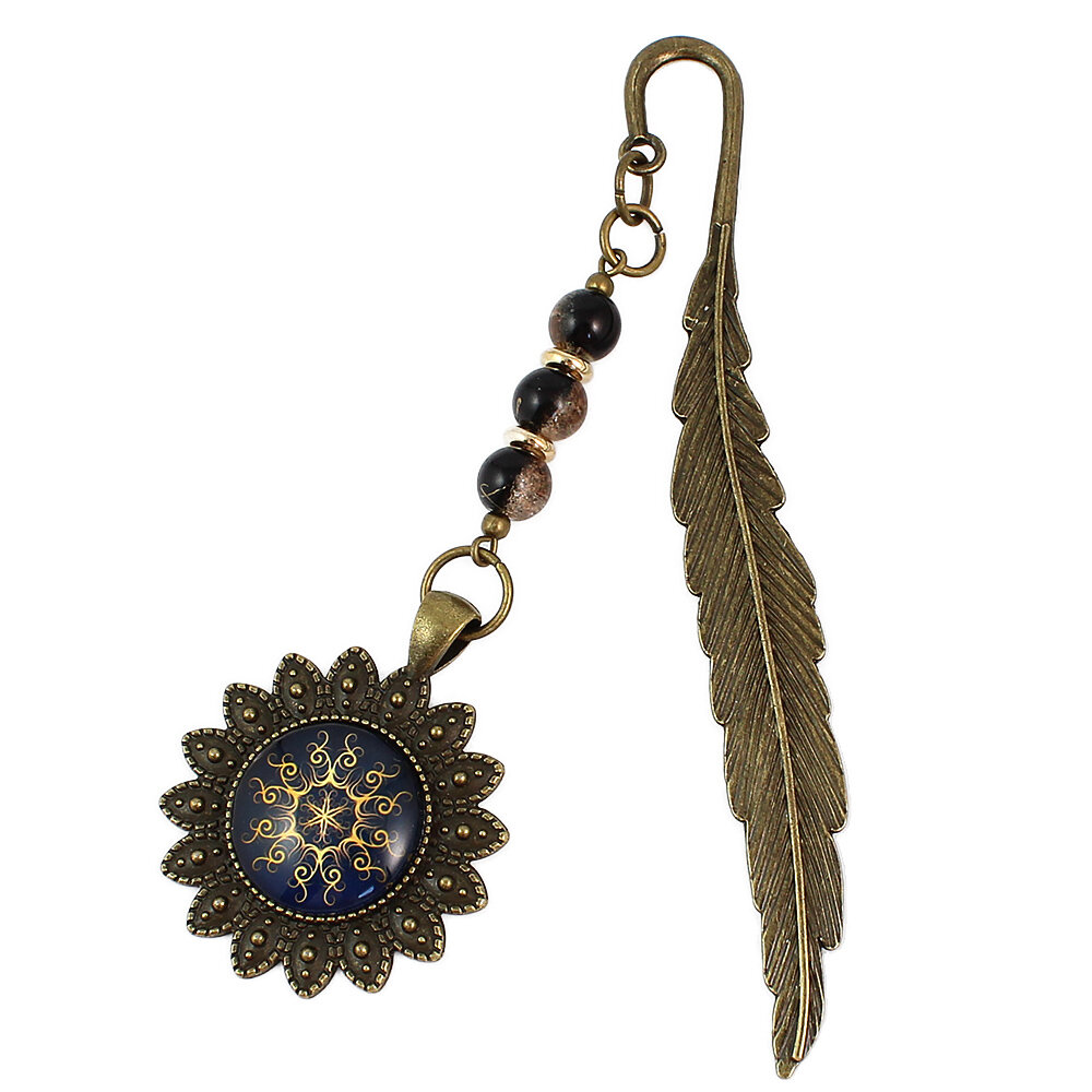 Zakładka do książki z antycznego brązu w kształcie pióra, z ozdobnymi koralikami oraz słoneczną, złotą mandalą na granatowym tle w oprawie z płatków