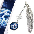 Srebrna zakładka do książki w kształcie piórka z ażurowym łącznikiem i zawieszką ze szklanym kaboszonem przedstawiającym magiczną mapę świata w klimacie fantasy