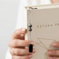 Cienka metalowa zakładka do książki pióro w kolorze grafitowym z zawieszką z czarnego onyksu i kulistego hematytu, w czarnym pudełku.