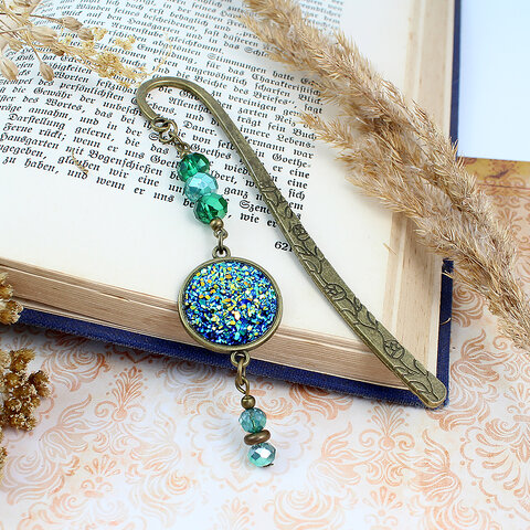 Zakładka do książki z antycznego brązu z motywem roślinnym, zielonymi kryształkami i mieniącą się, błyszczącą druzą z żywicy.