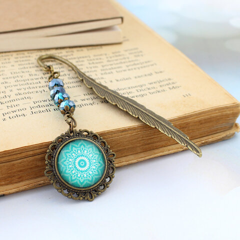 Zakładka do książki piórko w kolorze antycznego brązu z turkusowymi kryształkami i zawieszką z mandalą pod szklanym kaboszonem Zakładka do książki piórko w kolorze antycznego brązu z turkusowymi kryształkami i zawieszką z mandalą pod szklanym kaboszonem