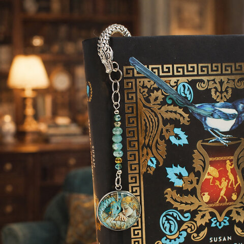 Srebrna zakładka do książki z trzonem w kształcie smoka, szklanymi kryształkami oraz zawieszką z grafiką śpiącej księżniczki i smoka