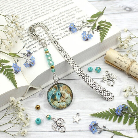 Srebrna zakładka do książki z trzonem w kształcie smoka, szklanymi kryształkami oraz zawieszką z grafiką śpiącej księżniczki i smoka