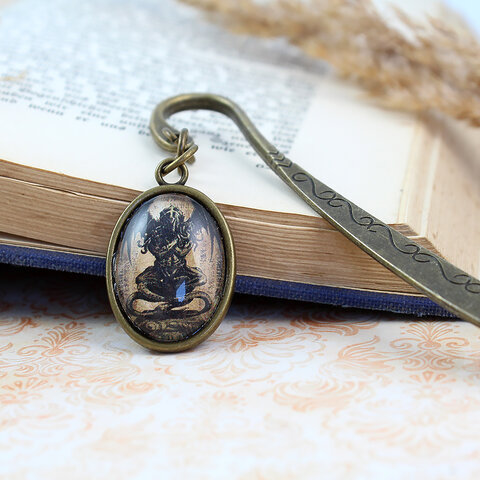 Zakładka do książki z antycznego brązu z owalnym szklanym kaboszonem przedstawiającym mroczny posążek Cthulhu inspirowany prozą Lovecrafta.