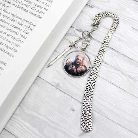 Zakładka do książki w kształcie smoka w kolorze antycznego srebra z grafiką czarownika/wojownika pod szklanym kaboszonem.