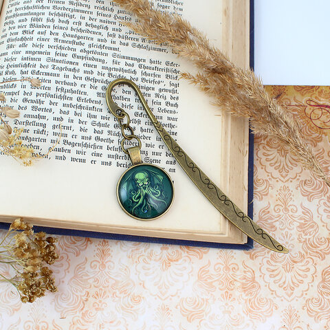 Zakładka do książki z antycznego brązu z graficznym przedstawieniem Przedwiecznego Cthulhu pod szklanym kaboszonem na tle zielonych odcieni.