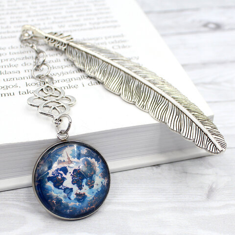 Srebrna zakładka do książki w kształcie piórka z ażurowym łącznikiem i zawieszką ze szklanym kaboszonem przedstawiającym magiczną mapę świata w klimacie fantasy