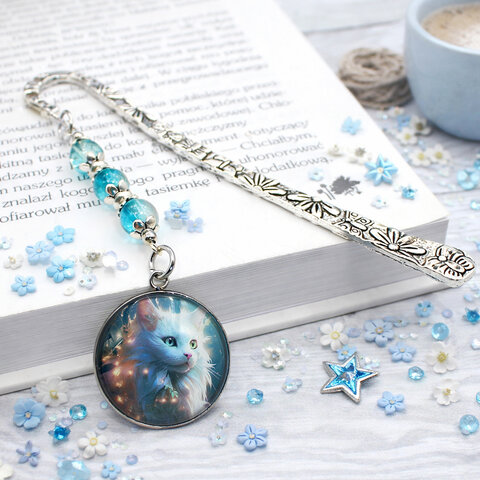 Srebrna zakładka do książki z metalowym trzonem w kwiaty i motyle, niebieskimi koralikami oraz zawieszką z autorską grafiką białego długowłosego kota