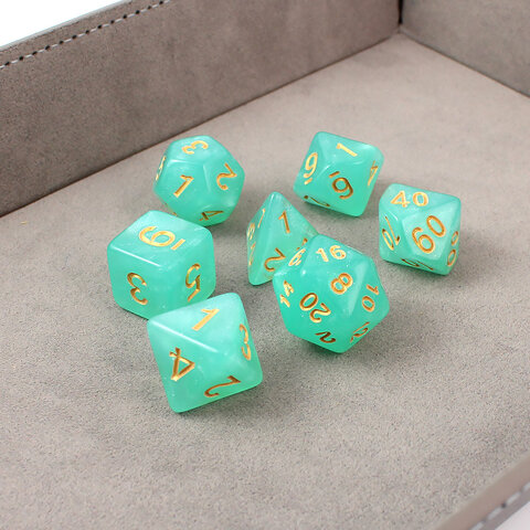 Turkusowe kości wielościenne do RPG ze złotymi cyframi i połyskiem. Turkusowe kości wielościenne do RPG ze złotymi cyframi i połyskiem.