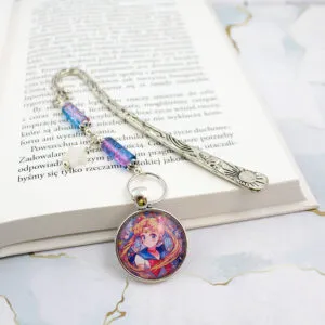 Metalowa zakładka do książki w kolorze antycznego srebra z grafiką Czarodziejki z Księżyca (Sailor Moon) pod szklanym kaboszonem, ozdobiona niebiesko-fioletowymi koralikami i gwiazdką.