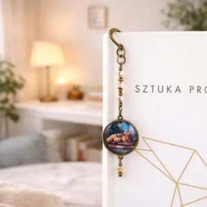 Zakładka do książki z antycznego brązu z zawieszką w kształcie gwiazdek oraz ilustracją śpiącego kota na stosie książek pod szkiełkiem.