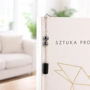 Cienka metalowa zakładka do książki pióro w kolorze grafitowym z zawieszką z czarnego onyksu i kulistego hematytu, w czarnym pudełku.